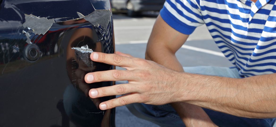 Car damaged in parking lot. Man checking car scratches and dents (Demo)