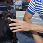 Car damaged in parking lot. Man checking car scratches and dents